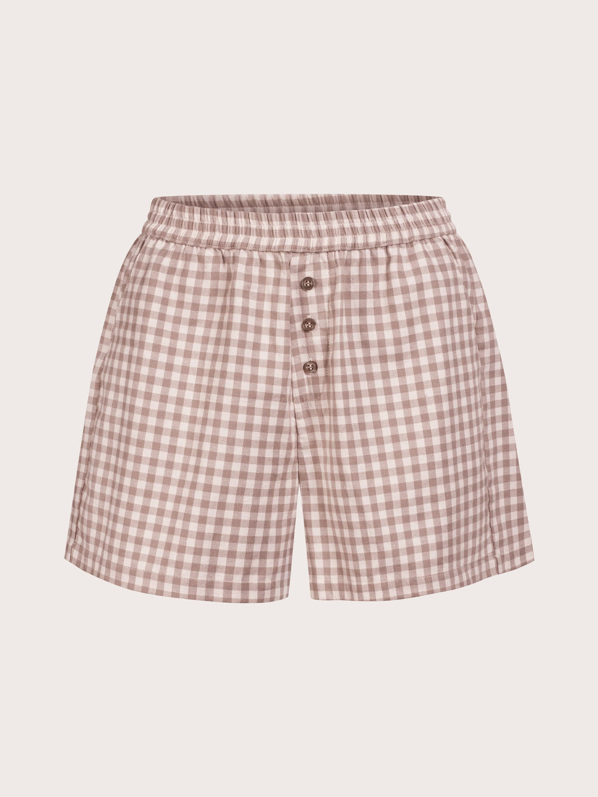 A pair of women's shorts featuring a pink and beige gingham check pattern, an elastic waistband, and a front button closure, shown against a solid light beige background.